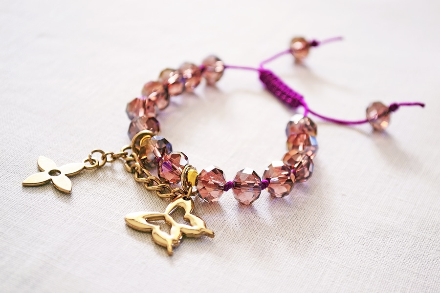 still life of bracelet with purple beads and gold charms